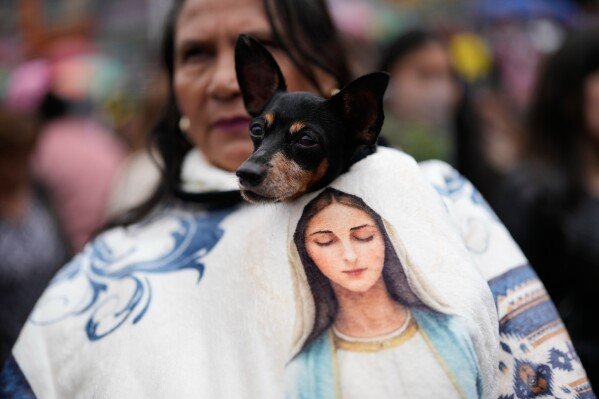 A woman and her dog attend a Mass on Palm Sunday, marking the start of Holy Week, at the Divine Child Church in Bogota, Colombia, Sunday, March 29, 2026. (AP Photo/Fernando Vergara)