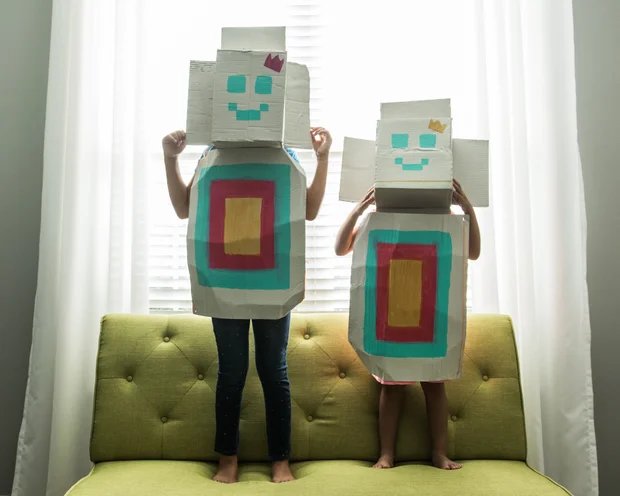 Young girls wearing homemade robot costumes at home