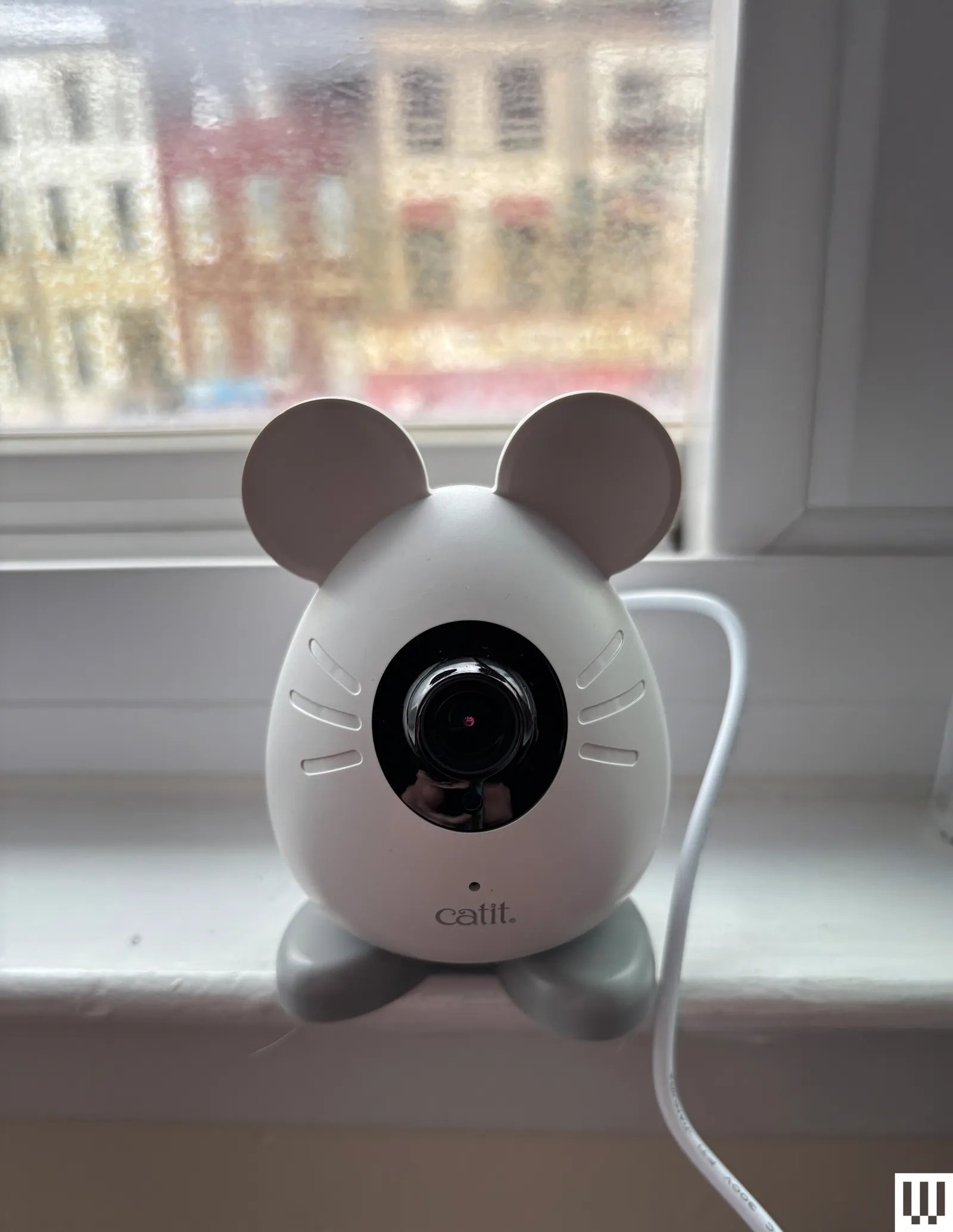 White mouseshaped pet camera sits on a white windowsill.