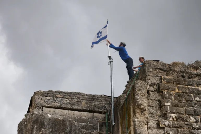 Israeli settlers place an Israeli flag atop a building, on the day of the re-establishment of the settlement of Sa-Nur, which was evacuated as part of Israel’s 2005 disengagement, in Sa-Nur in the Israeli-occupied West Bank, April 19, 2026. REUTERS/Shir Torem TPX IMAGES OF THE DAY