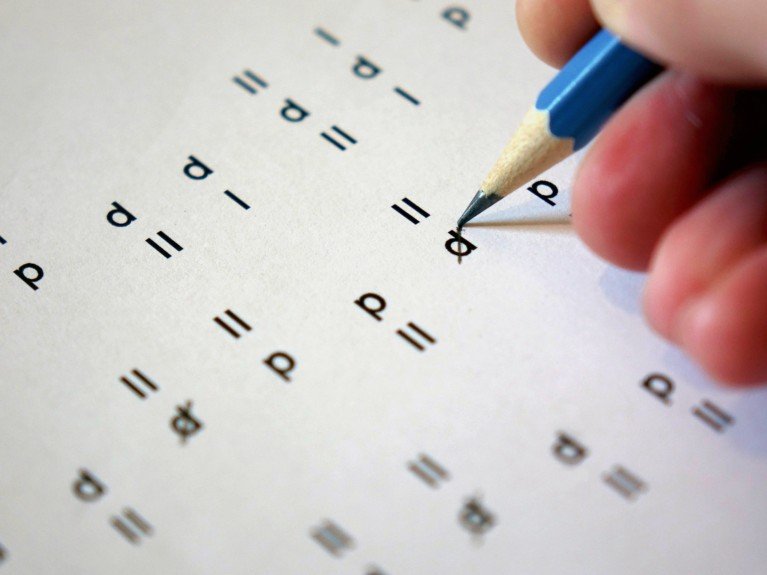 A close up view of a pencil marking characters on a d2 test paper.