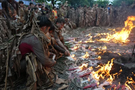 Catholics covered in mud and dried banana leaves light candles as they participate at the mud people festival on the feast day of Saint John the Baptist at Bibiclat, Nueva Ecija province, northern Philippines on Wednesday, June 24, 2026. (Credit: Aaron Favila/AP.)