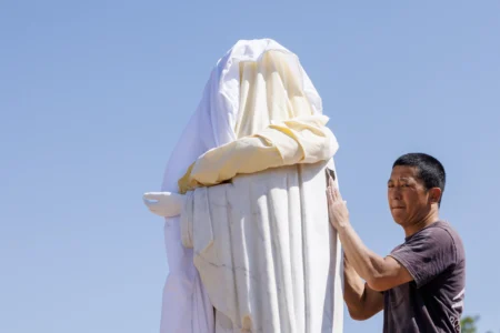 Volunteer cleans the vandalized statue of the Virgin Mary, which has been covered with a white sheet, on Apparition Hill in Medjugorje, Bosnia, Tuesday, July 28, 2026. (Credit: AP Photo/AP.)