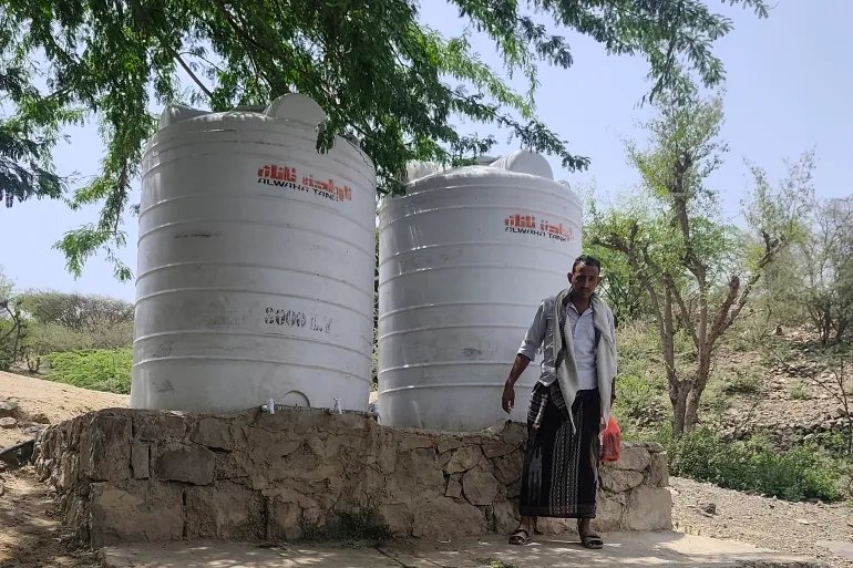 Abdulaziz Shamsan stands beside water tanks near the camp for displaced families where he lives [Courtesy of Abdulaziz Shamsan]