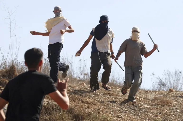 Masked Israeli settlers attack Palestinians in the West Bank village of Assira al-Kibliya. [File: Nasser Ishtayeh/AP]